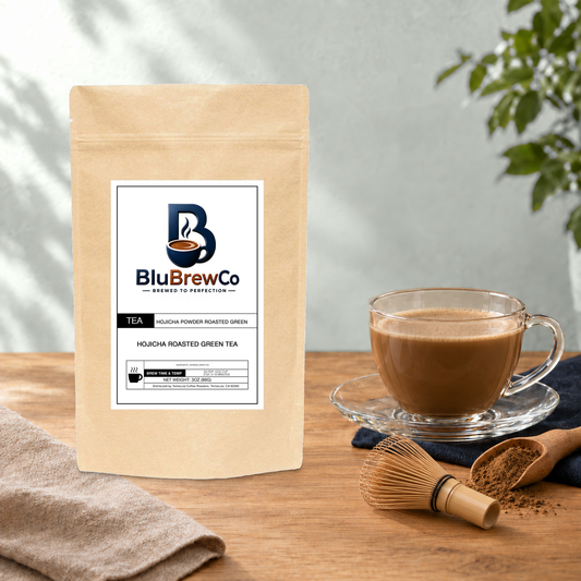 BluBrewCo Hojicha original bag with powder, bamboo whisk and a prepared drink, on warm wood against a sea-salt wall