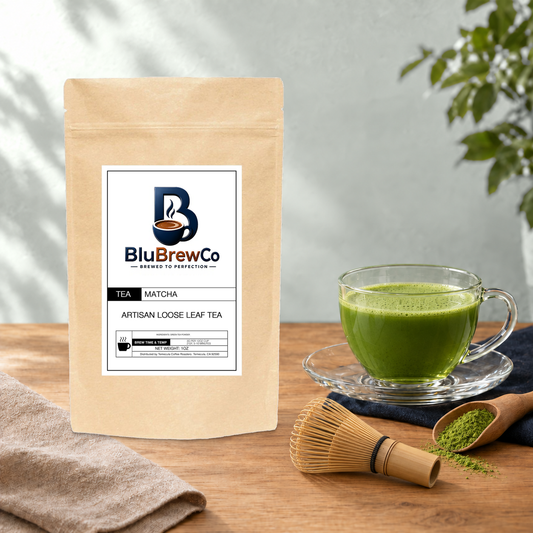 BluBrewCo Matcha original bag with powder, bamboo whisk and a prepared drink, on warm wood against a sea-salt wall